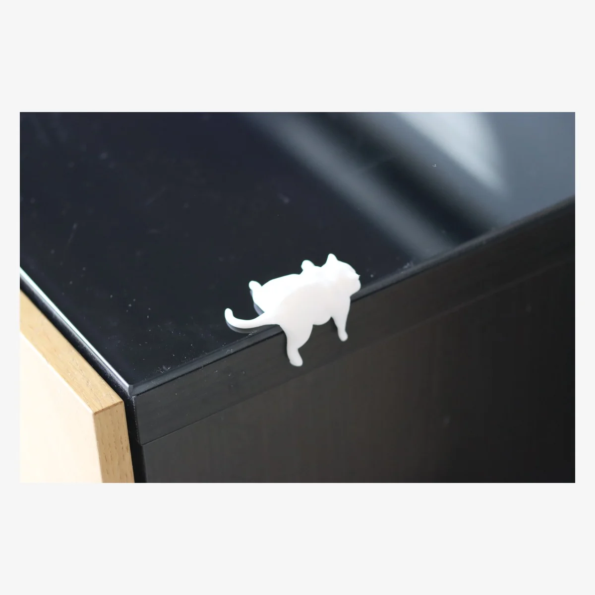 Cream sleepy cat shelf-edge figure displayed on a black shelf